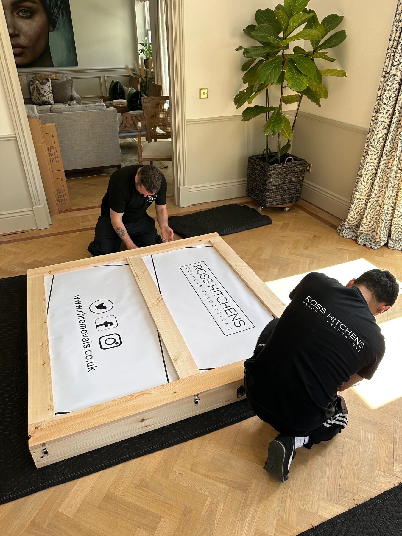 Two RH team members building a bespoke wooden crate in a client's home