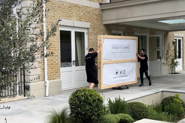 RH team carrying a large crated item out of a house
