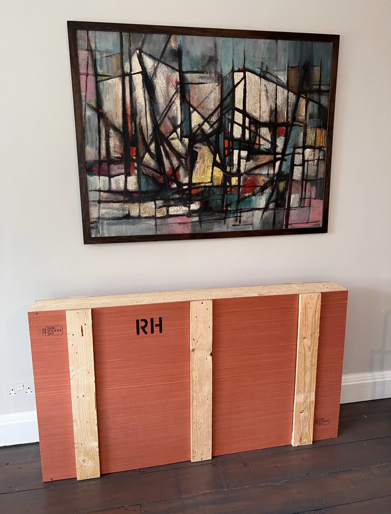 A console table protected in a bespoke RH crate beneath a painting