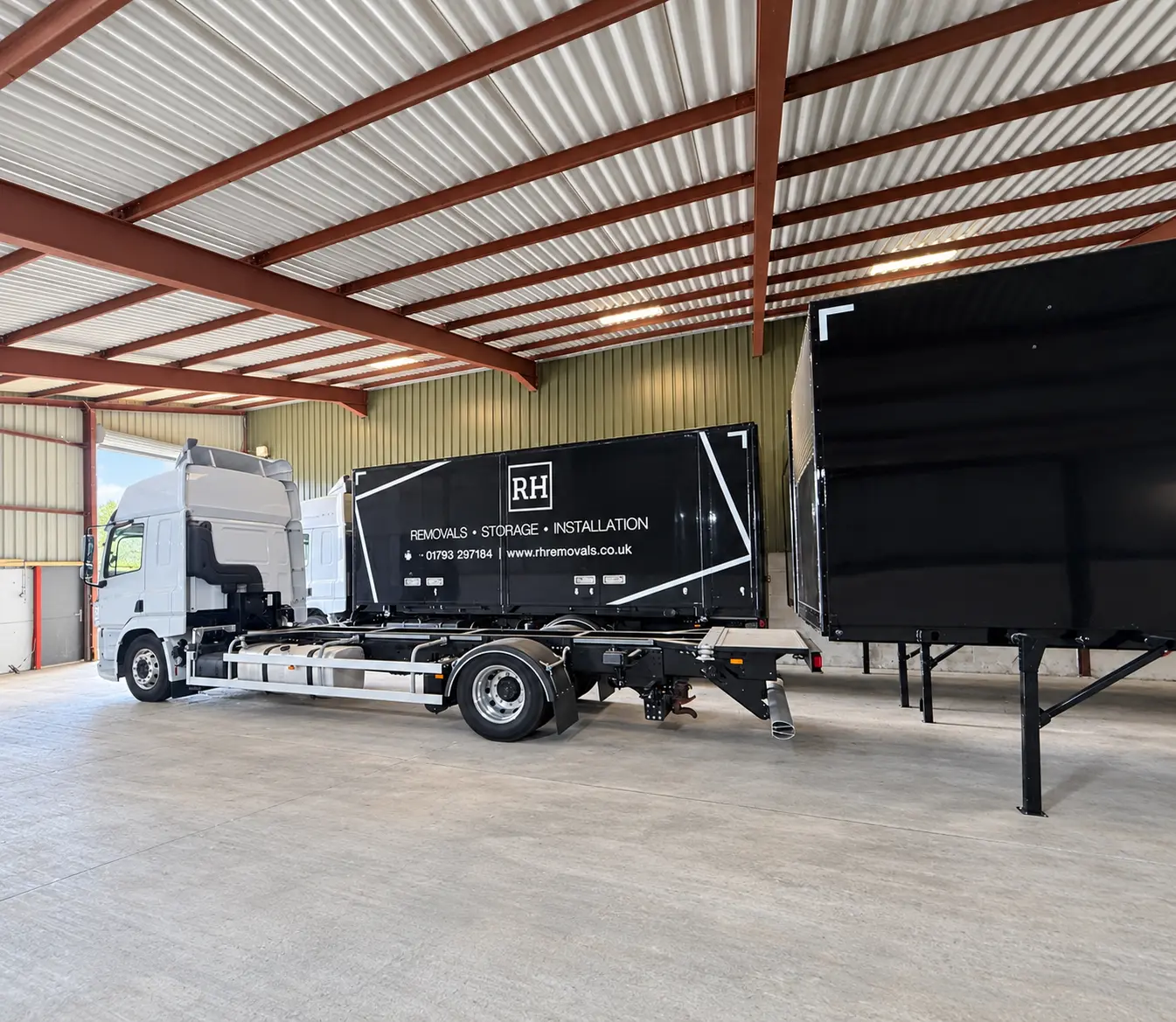RH lorry carrying a de-mount body inside the RH storage building, beside a body standing on its legs
